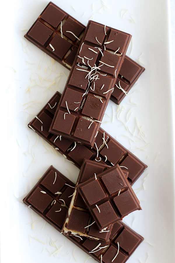 Chocolate bars layered with pistachio pudding and kataifi stacked on a white plate.